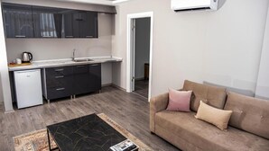 A compact living space with a kitchenette, a sofa, and a coffee table. - Comfort Center (Edirne)