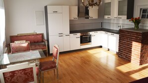 Eine moderne Küche mit weißen Schränken, einem Kamin aus Ziegelsteinen und einem Essbereich mit rot gepolsterten Stühlen.