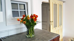 Ein Zimmer mit Fenster, Tür und einer Tischvase mit Blumen ist gut sichtbar.