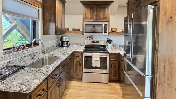 A kitchen with wooden cabinets, stainless steel appliances, and a granite countertop.