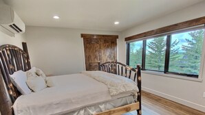 A bedroom with a wooden bed, a large window, and a wooden headboard.