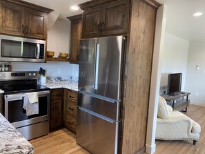 A modern kitchen with wooden cabinets, stainless steel appliances, and a marble countertop. - New one-bedroom upstairs apartment near Teton Canyon (Driggs)