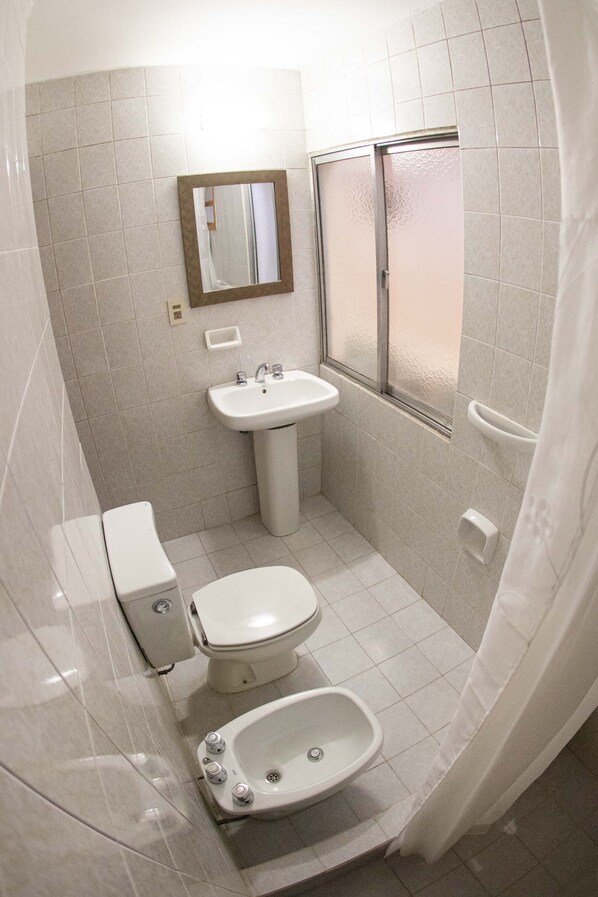 A small, compact bathroom with a toilet, sink, and bidet.