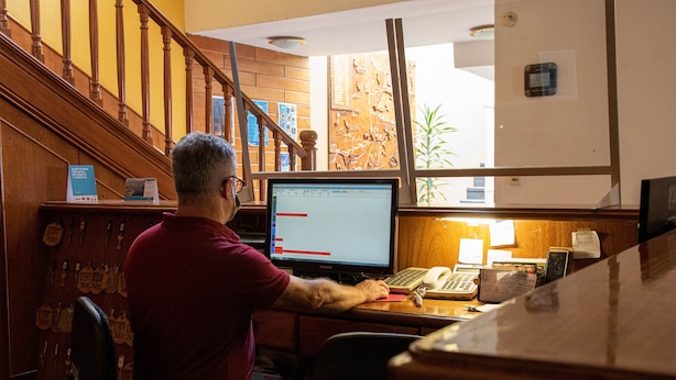 A man working at a desk with a computer and a telephone. - Hotel Provincia (Trelew)