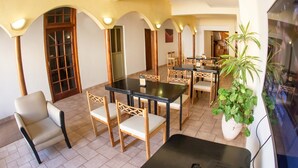 A hotel dining area with tables and chairs, a television, and a potted plant. - Hotel Provincia (Trelew)