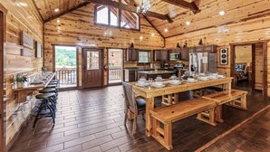Uma cabana rústica de madeira com cozinha, sala de jantar e balcão.
