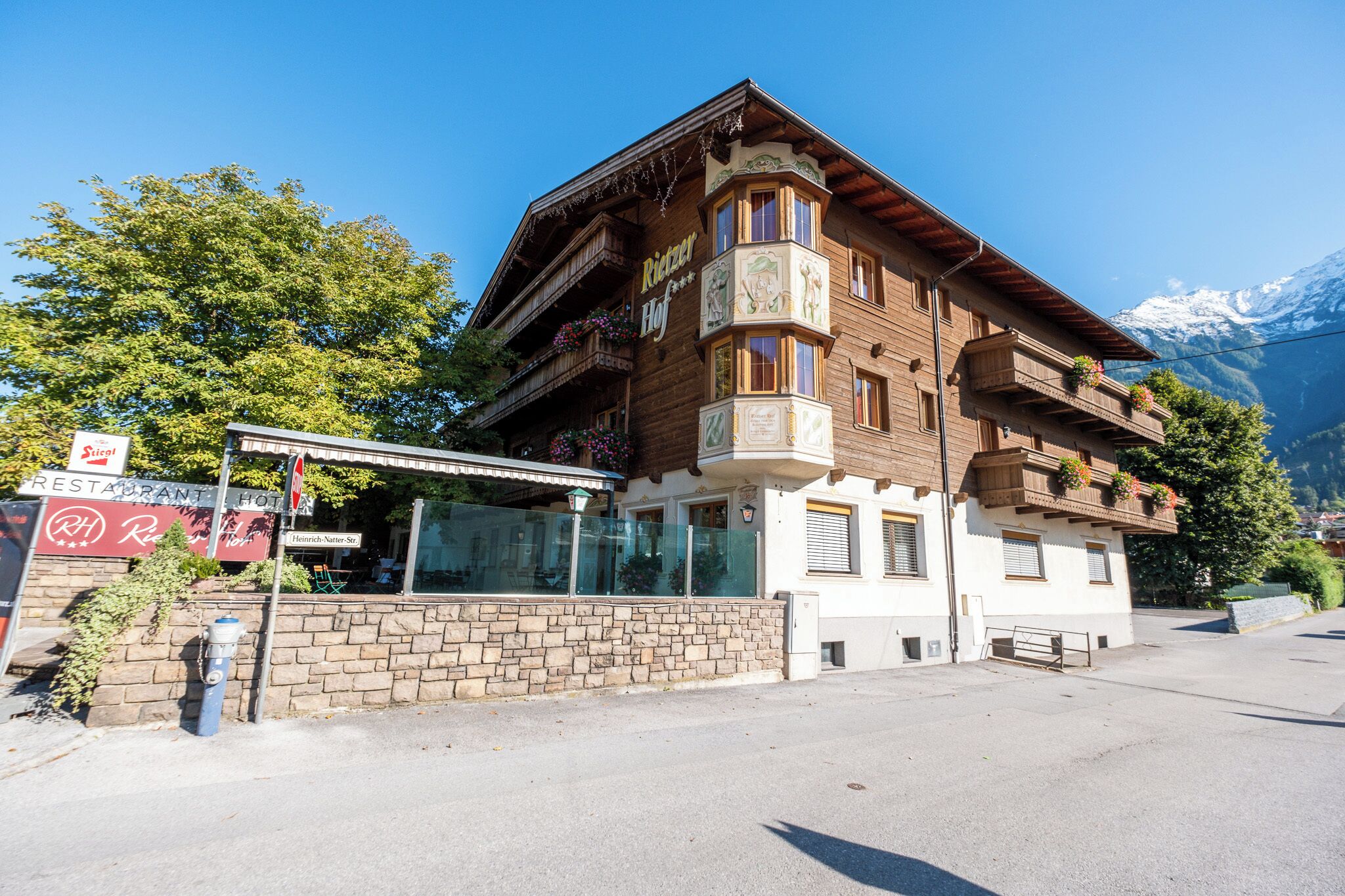Un edificio de madera tradicional con balcones, un letrero de restaurante y montañas al fondo.