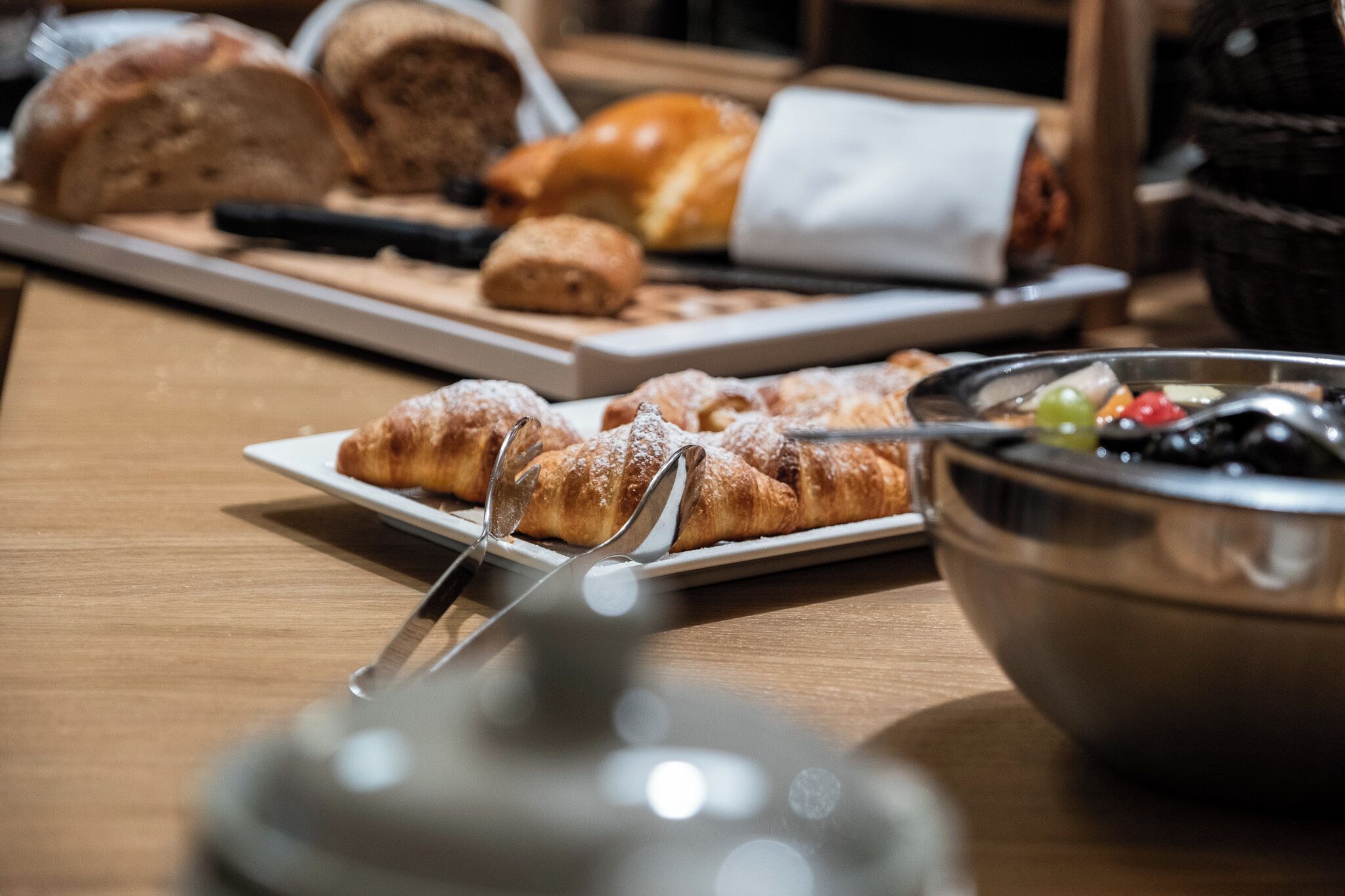 A table with various pastries and a bowl of fruit.