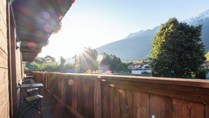 A wooden deck with tables and chairs, overlooking a mountainous landscape.