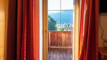 A wooden door with a view of a balcony and mountains in the background.