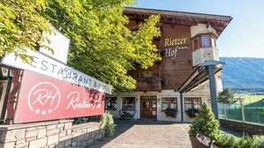 A wooden building with a sign reading "Rietzer Hof" and a sign for "RESTAURANT & HOTEL".