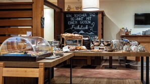 A breakfast buffet with various food items, a chalkboard with a message, and wooden furniture.