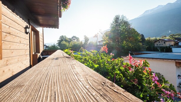 A wooden deck with a view of a mountain and a building with a wooden facade.