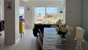 Ein Essbereich mit Blick auf den Strand, ein Tisch mit Kerze und eine Blumenvase.