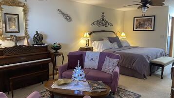 Ein gemütliches Schlafzimmer mit einem Bett, Nachttischlampen, einem Klavier, einem kleinen Weihnachtsbaum und einem Wandkunstwerk.