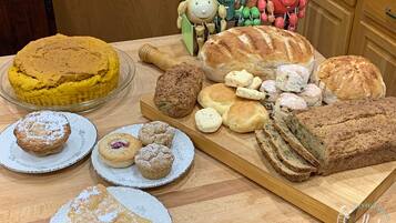 A variety of baked goods including cakes, pastries, and bread on a wooden table.