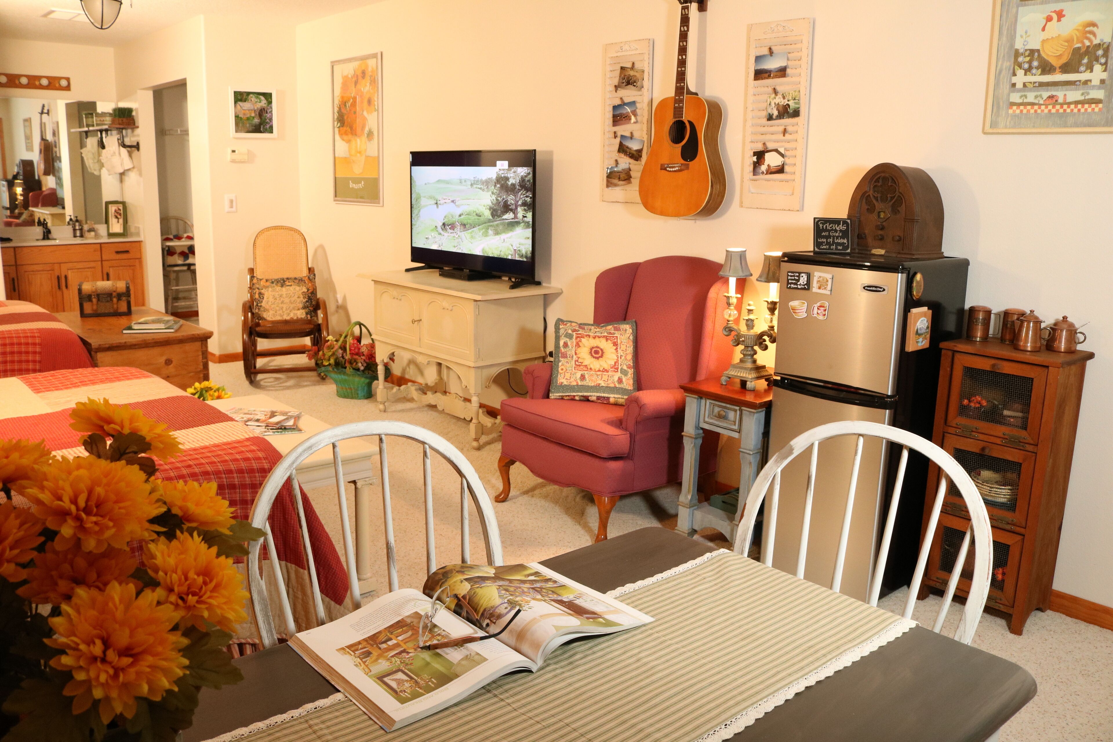 Een gezellige woonkamer met een televisie, een gitaar en een koelkast.