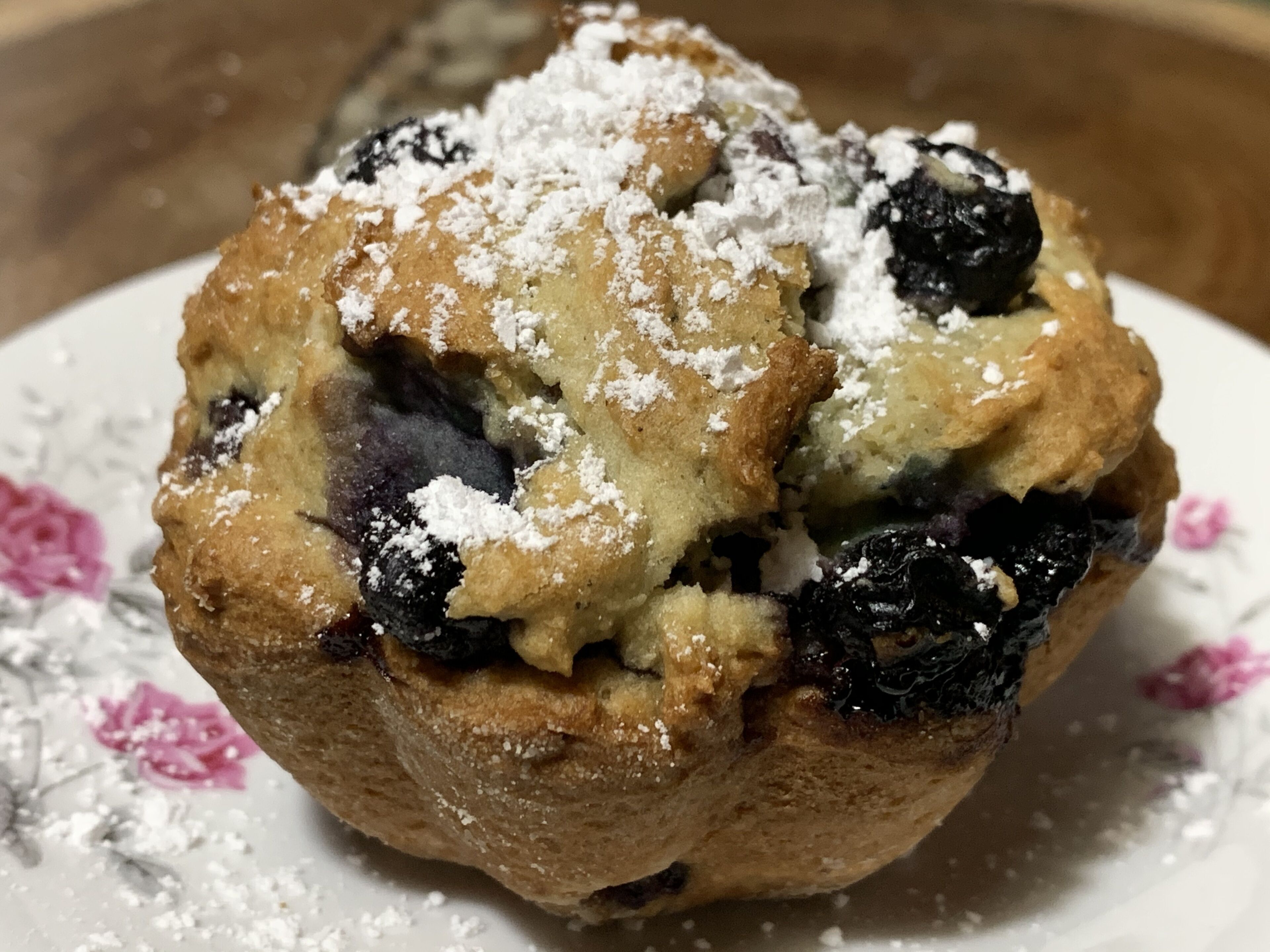 Un muffin con arándanos y azúcar glas sobre un plato.