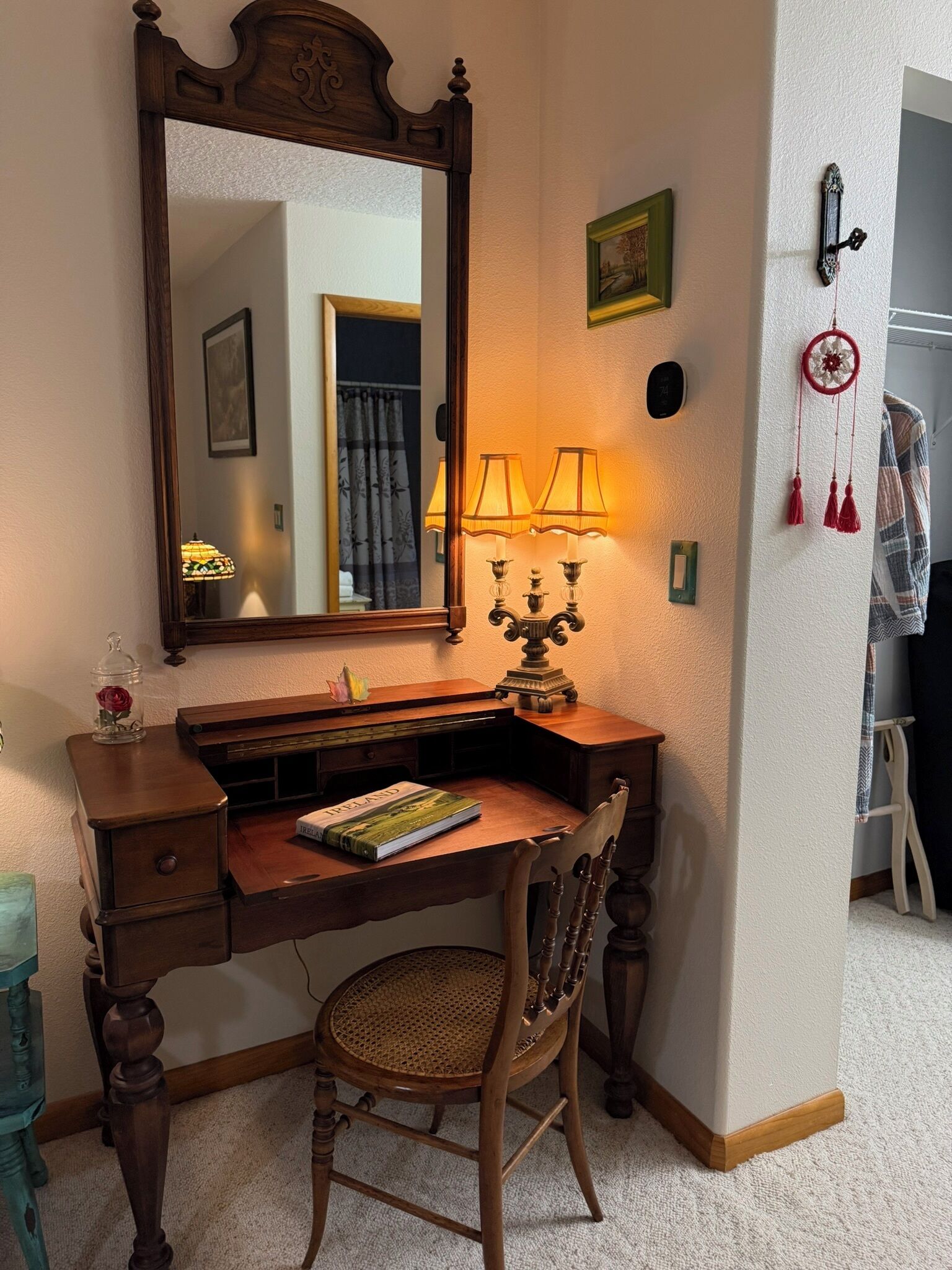 A wooden desk with a mirror, a lamp, and a book titled "Ireland" on it.