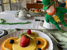 Una mesa dispuesta con un plato de fruta, una tetera y una figurita de duende.