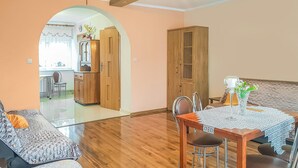 A dining area with a wooden table, chairs, and a decorative centerpiece. There is a wooden cabinet and an arched doorway leading to another room. - Cozy apartment in Dominikowo with WiFi (Dominikowo)