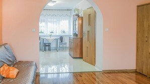 A living room with a sofa, a glass partition, and a view into a dining area with a table and chairs. - Cozy apartment in Dominikowo with WiFi (Dominikowo)