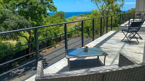 A balcony with a view of the ocean, a table with a potted plant, and outdoor seating. - Oceanview, Minigolf, Pool, 2BR & Office. 5 min to Coco Beach (Coco)