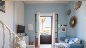 Una sala de estar con un sofá azul, una mesa de comedor y una escalera.