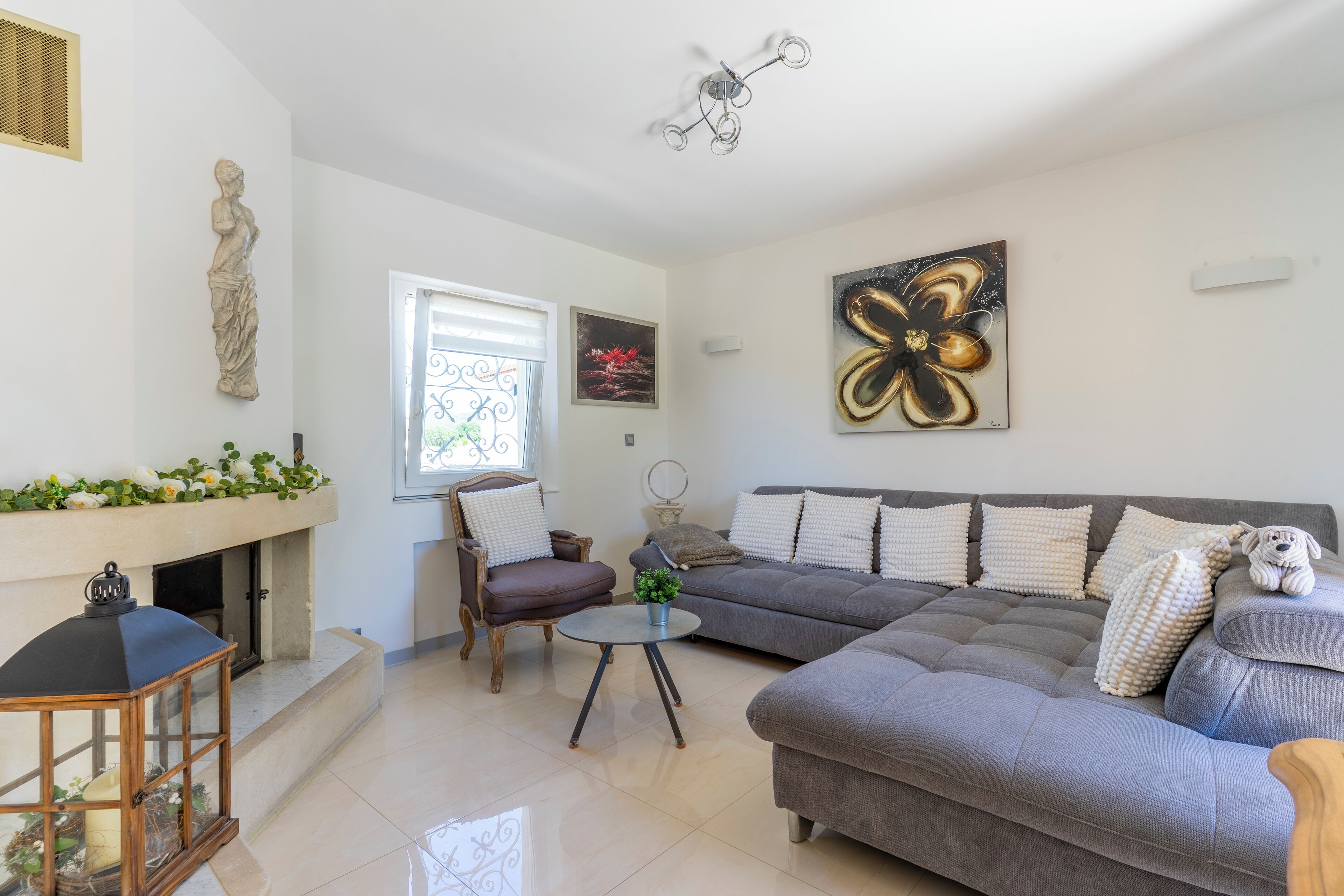 Ein modernes Wohnzimmer mit Kamin, einem grauen Sofa, einem runden Couchtisch und einer dekorativen Statue.