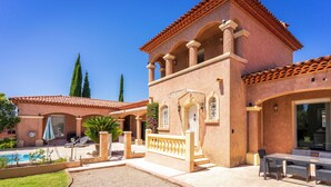 A Mediterranean-style villa with a pool, outdoor seating, and a well-maintained garden.
