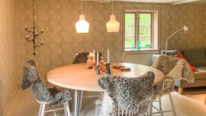Een eetruimte met een ronde tafel, witte stoelen en een kroonluchter.