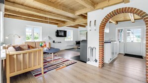 Un vaste espace de vie doté d’un plafond en bois, d’un canapé, d’une table basse et d’un téléviseur.