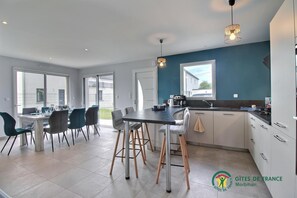 A modern kitchen with white cabinets, a black countertop, and a window. There is a dining area with a table and chairs.