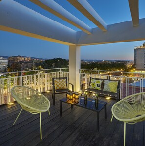 A balcony with wicker chairs, a table with bottles and glasses, and string lights. - Apartamento con Terraza, Preciosas Vistas, Parking (Granada)
