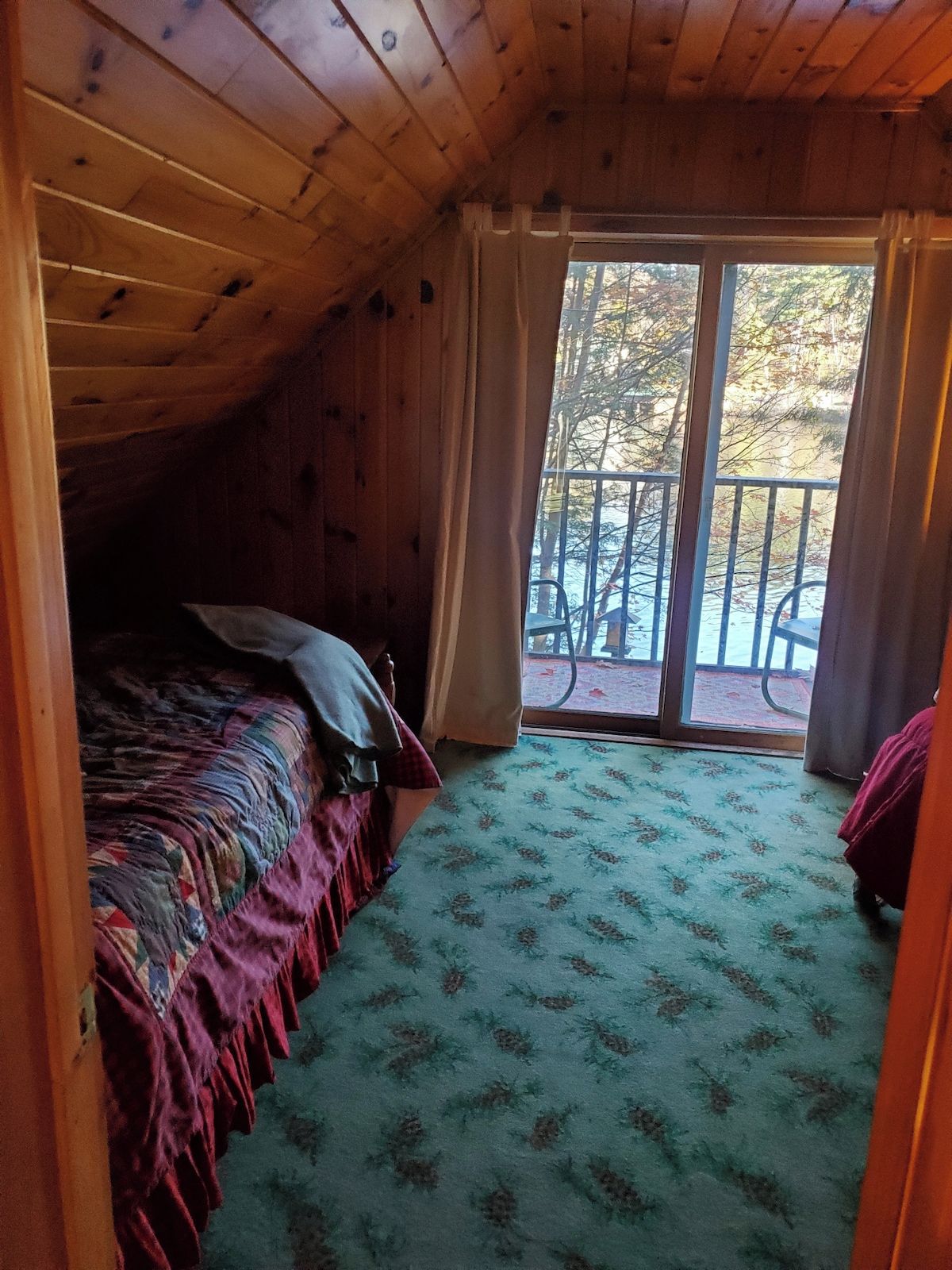 A room with a bed, a window, and a view of the outdoors.