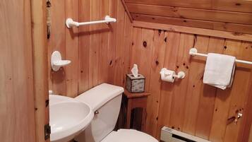A wooden-paneled bathroom with a toilet, sink, and towel rack.