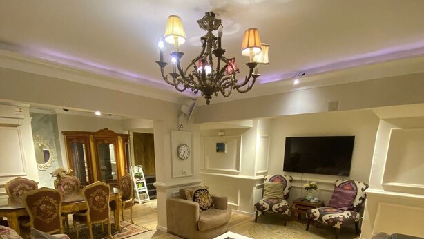 A living room with a chandelier, sofas, a coffee table, and a television. - Lovely apartment in the heart of Cairo (Cairo Governorate)