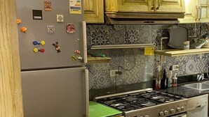 A kitchen with wooden cabinets, a refrigerator, a stove, and a microwave. - Lovely apartment in the heart of Cairo (Cairo Governorate)