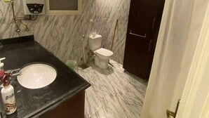A bathroom with a marble floor, a black sink, a toilet, and a shower curtain. - Lovely apartment in the heart of Cairo (Cairo Governorate)