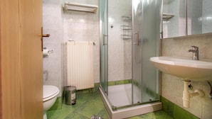 A bathroom with a toilet, a sink, a glass-enclosed shower, and a radiator. - Lovely apartment in Portoroz with house sea view (Portoroz)