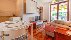 A compact living space with a kitchenette, a television, a sofa, and a balcony with a view. - Lovely apartment in Portoroz with house sea view (Portoroz)