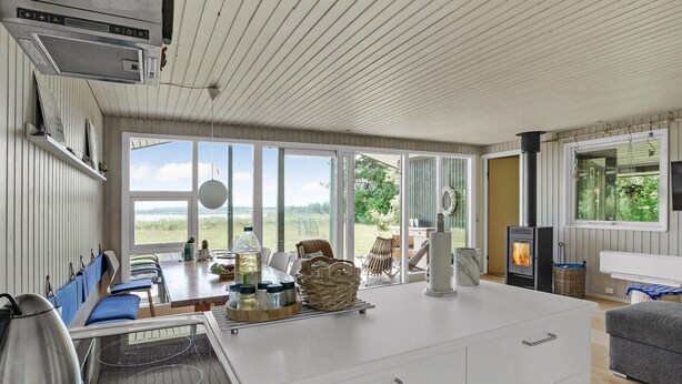 A spacious room with a large window, a fireplace, and a dining area. - Lovely home in Spøttrup (Spøttrup)