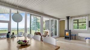 A spacious room with a large wooden table, white chairs, and a view of the outdoors. - Lovely home in Spøttrup (Spøttrup)