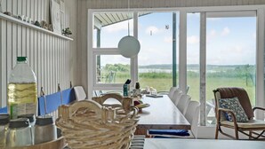 A dining area with a long table, chairs, and a view of a grassy field through large windows. - Lovely home in Spøttrup (Spøttrup)