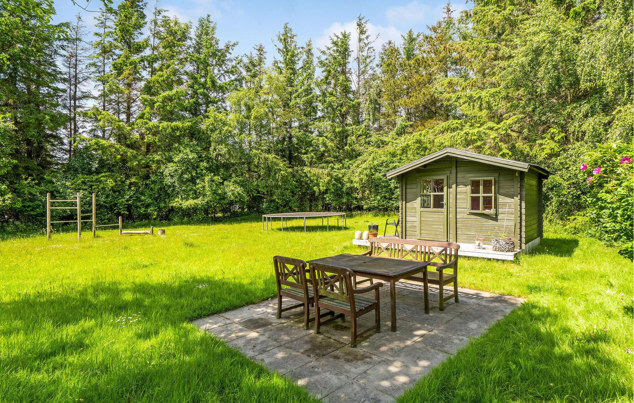 A rustic wooden cabin with a porch, surrounded by lush green grass and trees.