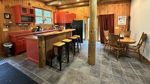Cocina rústica con paredes de madera y una isla central con taburetes.