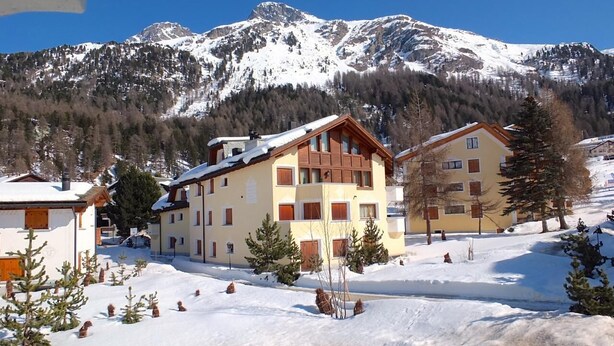 A snow-covered mountain resort with multi-story buildings, a ski slope, and a clear sky. - Charming apartment on the 1st floor, elevator, Entrée with wardrobe, living and  (Silvaplana-Surlej)