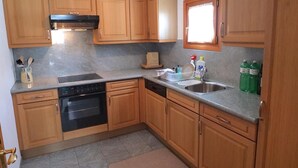 A kitchen with wooden cabinets, a built-in oven, a dishwasher, a sink, and a window above the sink. - Charming apartment on the 1st floor, elevator, Entrée with wardrobe, living and  (Silvaplana-Surlej)