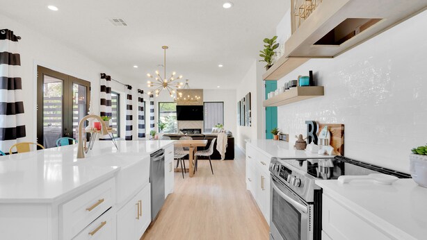 Une cuisine moderne avec des meubles blancs, un îlot central et un coin repas avec des chaises.
