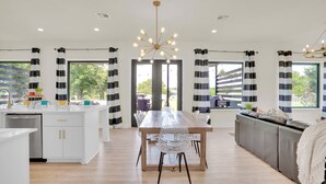 Une cuisine moderne dotée d’un îlot central, de meubles blancs et d’un coin repas avec une table et des chaises en bois.